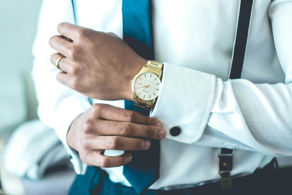 Executive Professional Look A professional man in a tailored suit adjusting his sleeve collar, showcasing executive style and attention to detail—reflecting the premium, corporate-level service of Princeton Elite Car Service